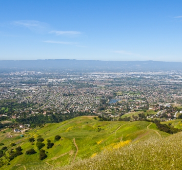 Looking down from green Sierra Vista hillsides across urban San Jose to the Santa Cruz Mountains in the hazy distance