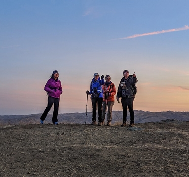 Four hikers at top of hill pointing to the distance