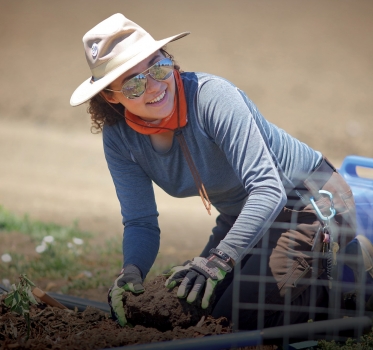 Smiling volunteer putting plant into ground