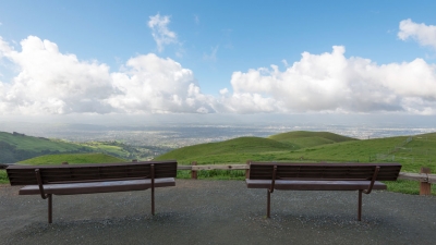 Two benches facing green hills and view of San Jose below in the distance