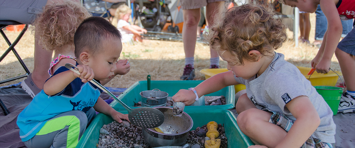 Two toddlers playing with a nature activity at an outdoor community event